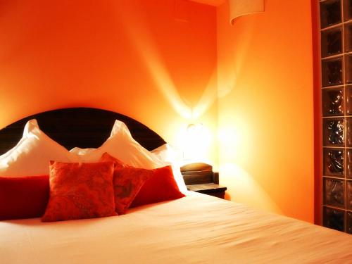 a bedroom with a bed with an orange wall at La Posada de Quijada in Granada