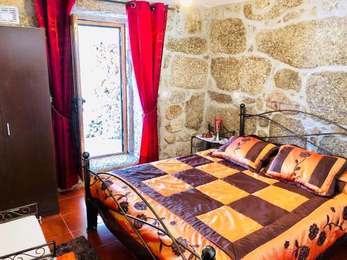 a bedroom with a bed and a stone wall at Casa da Quinta da Prelada Simão partie basse in Celorico de Basto