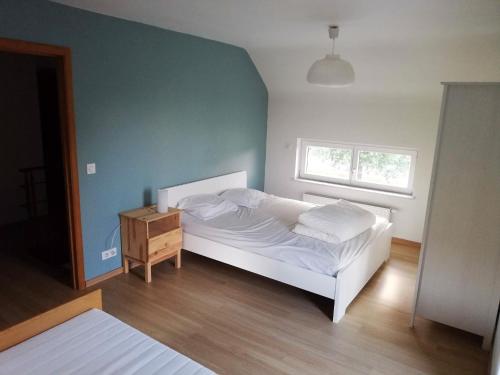 a bedroom with a white bed and a wooden floor at Entre Sève Et Ciel in Tillet