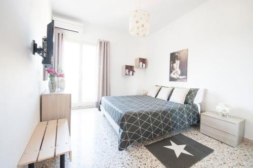 a white bedroom with a bed and a bench at Casa Vacanze La Meridiana in Modica