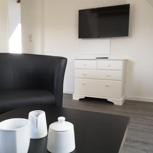 a living room with a black chair and a white dresser at Haus Worch in Juist
