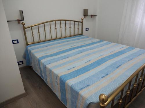 a bed with a blue and white striped blanket on it at Casa Vacanza Trabocco in Vasto