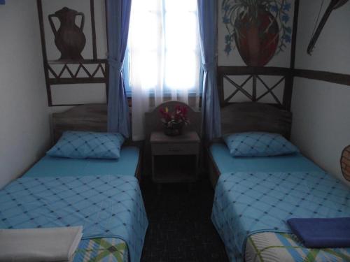 two beds in a small room with a window at GökMavi Pansiyon in Bodrum City