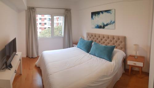 a bedroom with a large white bed with blue pillows at Encantador departamento con cochera cubierta in Vicente López