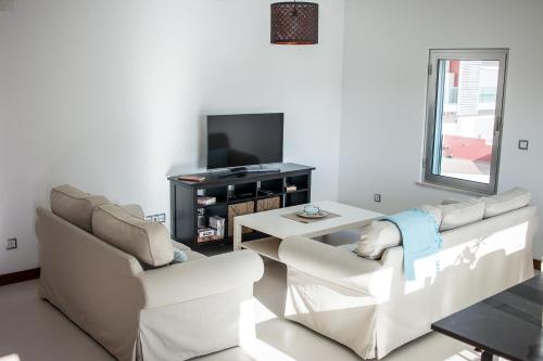 uma sala de estar com dois sofás brancos e uma televisão em RestlessWave em Peniche