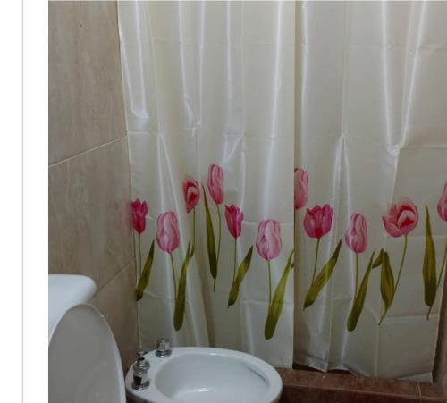 a bathroom with a shower curtain with pink tulips on it at Santo Domingo in Esquina
