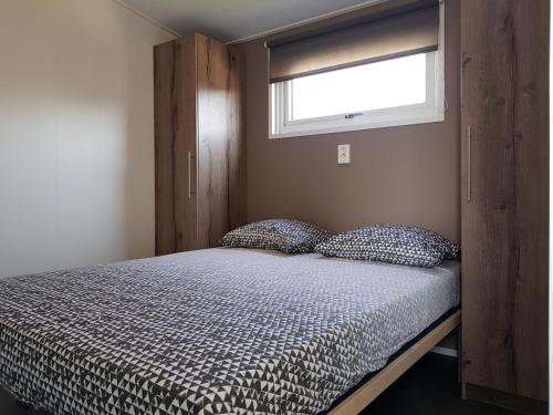 ein Bett in einem Schlafzimmer mit einem Fenster und einem Bett sidx sidx sidx in der Unterkunft Chalet 15 (Resort Venetië) in Giethoorn