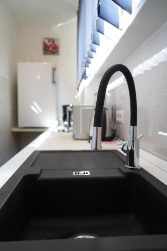 a kitchen sink with a black counter top at Apartments Edi & Tea in Malinska