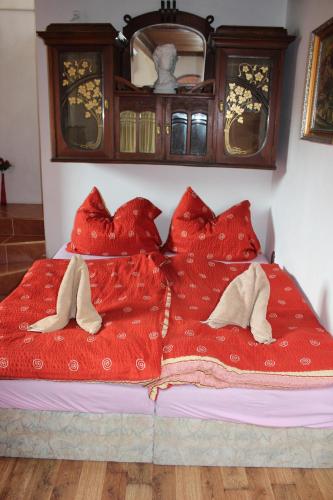 a bed with red blankets and pillows on it at Penzion St. Florian Příbor in Příbor