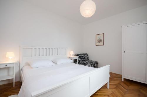 a white bedroom with a white bed and a chair at Apartment RUZA in Lopar