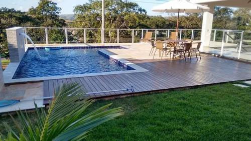 - une piscine avec une table, des chaises et un parasol dans l'établissement CASA UTOPIA ESCARPAS do LAGO, à Capitólio