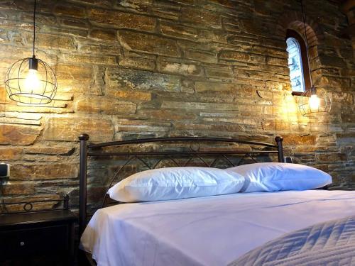 a bed with two pillows in a stone wall at Relax in a stone build dovecote in Andros