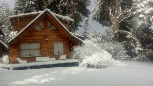 a log cabin with snow in front of it at Cabaña Naxara III in Villa La Angostura