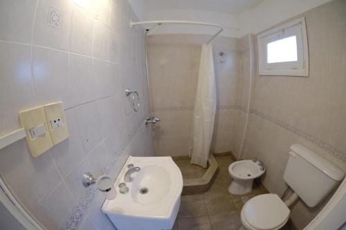 a white bathroom with a toilet and a sink at Bagu Playa Grande Hotel in Mar del Plata