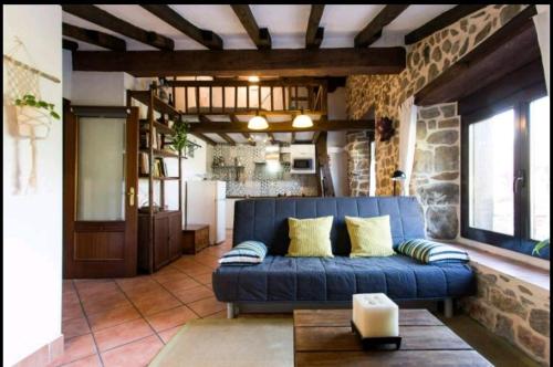 a living room with a blue couch and a stone wall at Casa con jardín y terraza privados, cerca del mar in Ea