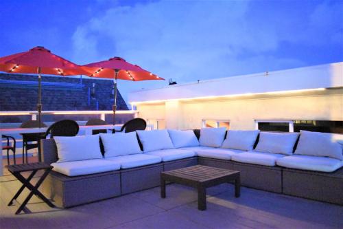 a white couch sitting on a patio with tables and umbrellas at Luv Oceanside Views-1 House to Beach, Boardwalk and Waves-Spacious Rooftop Sun Deck-Plus King Beds too! in San Diego