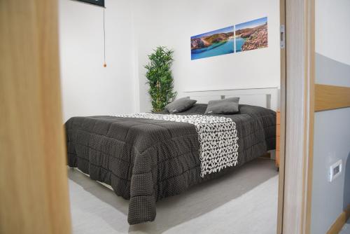 una camera con un letto con una coperta bianca e nera di Bed and Breakfast Porto Flavia a Iglesias