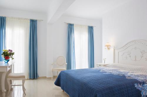 a bedroom with a blue bed and blue curtains at Kamari Hotel in Platis Yialos Mykonos