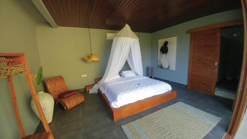 a bedroom with a bed with a mosquito net at Coco Garden Pool Villas in Kubutambahan