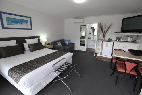 1 dormitorio con 1 cama y escritorio con TV en Mornington Motel en Mornington
