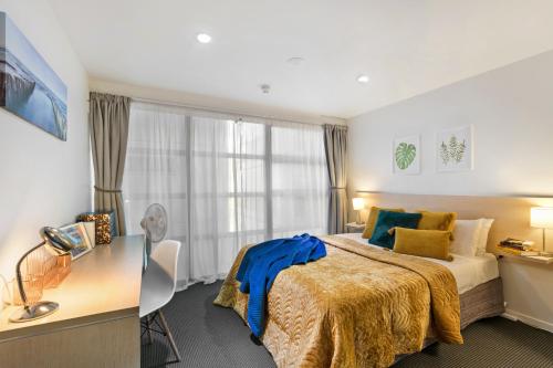a bedroom with a bed and a desk and a window at Deluxe Apartment with Sofa Bed - Sleeps 2 in Auckland