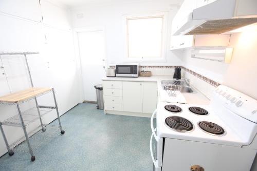 a white kitchen with a stove and a sink at Mornington Motel in Mornington