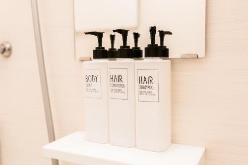 a shelf with four bottles of hair products on it at Bunkyo-ku Hakusan House in Tokyo