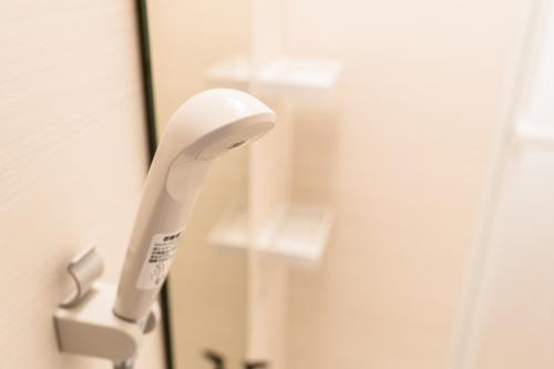 a white electric toothbrush hanging from a mirror at Bunkyo-ku Hakusan House in Tokyo