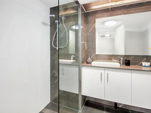 y baño con armarios blancos y ducha acristalada. en Luxury waterfront sea view apartment - do not book, en Cairns