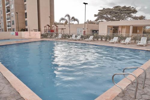 una gran piscina con sillas y un edificio en blue apartments en Cali