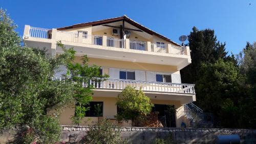 a large white building with a balcony and trees at Kallimos in Vasiliki
