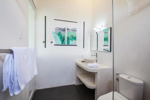 a white bathroom with a toilet and a sink at Ohana Retreat Bali in Mengwi