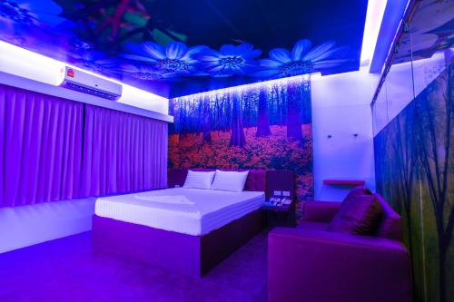 a bedroom with a bed and a chair and purple lighting at Sweety Resort in Bangna