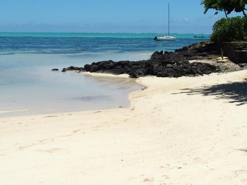 a sandy beach with a boat in the water at Villa Ximun in Roches Noires