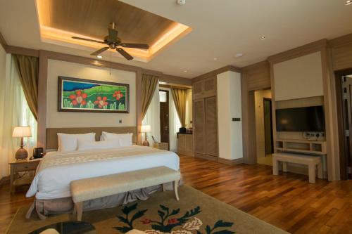 a bedroom with a large bed and a flat screen tv at Royale Chulan Cherating Villa in Cherating