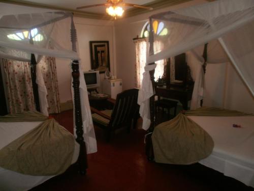 a bedroom with two canopy beds and a desk at Asmini Palace Hotel in Zanzibar City