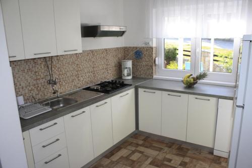 a white kitchen with white cabinets and a sink at Holiday Home Radmila in Premantura
