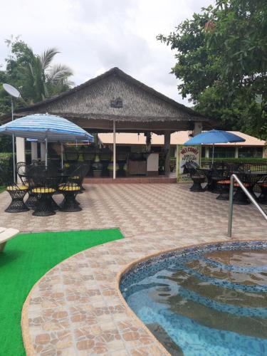 a patio with tables and umbrellas next to a pool at Monty's Riverside View Resort in San Antonio