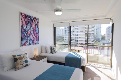a bedroom with two beds and a large window at Bougainvillea Gold Coast Holiday Apartments in Gold Coast