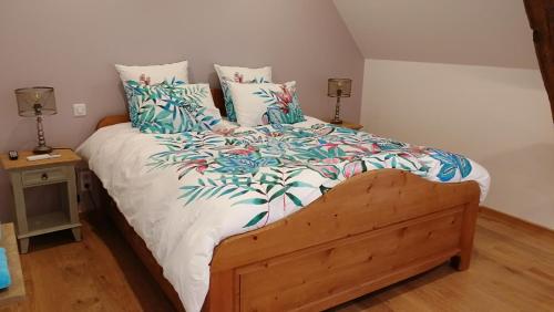 a bedroom with a large bed with blue and green pillows at L'Amalgam' in Ainay-le-Vieil