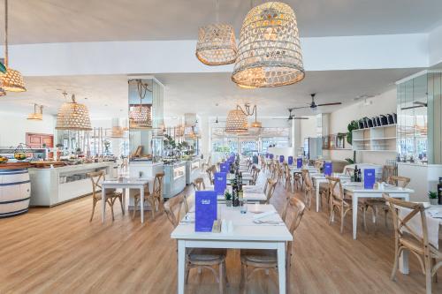 a restaurant with tables and chairs and a kitchen at FERGUS Style Soller Beach in Port de Soller