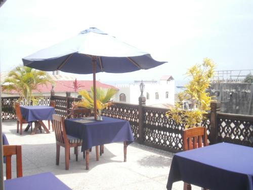 a patio with blue tables and an umbrella at Asmini Palace Hotel in Zanzibar City