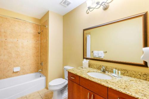 een badkamer met een wastafel, een toilet en een spiegel bij Clarion Inn Ormond Beach at Destination Daytona in Ormond Beach