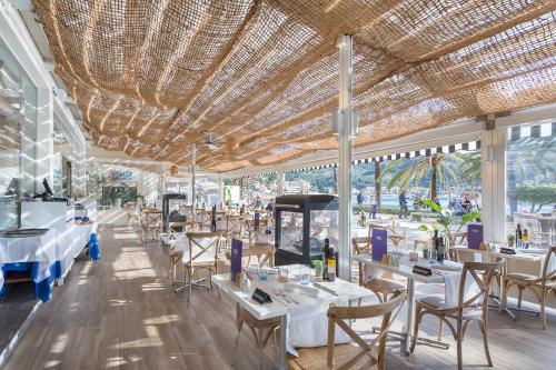 a restaurant with white tables and chairs and ceilings at FERGUS Style Soller Beach in Port de Soller