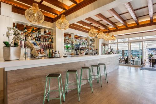 a bar with three green stools at a counter at FERGUS Style Soller Beach in Port de Soller