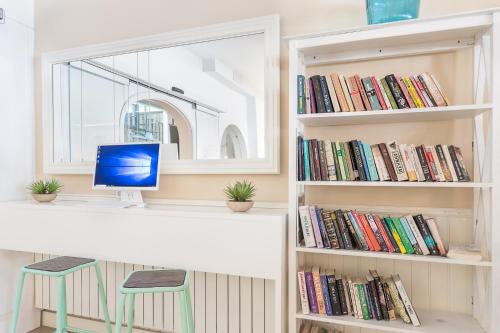 a desk with a computer on a shelf with books at FERGUS Style Soller Beach in Port de Soller