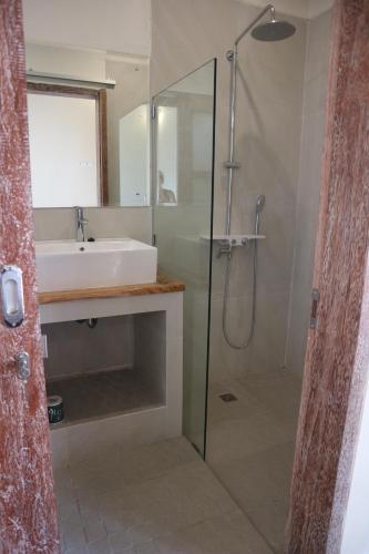 a bathroom with a sink and a shower with a glass door at Lazy Inn Kuta Lombok in Kuta Lombok