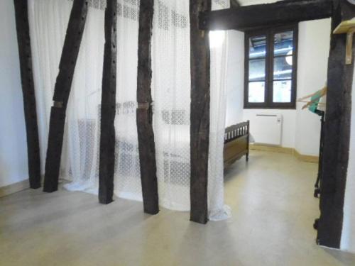 Zimmer mit einem Vorhang, einem Bett und einem Fenster in der Unterkunft Le trou dans le mur in Uzerche