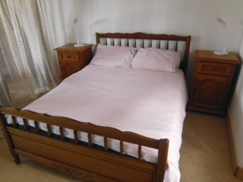 a bedroom with a bed with white sheets and two night stands at Le trou dans le mur in Uzerche