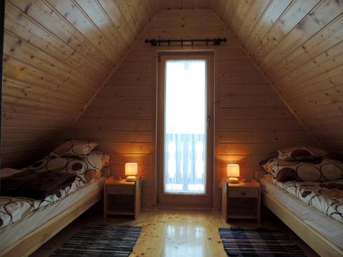 two beds in a attic room with a window at Edwardówka 601-130-636 - lipiec - sierpień - basen w cenie wynajmu domku in Polańczyk